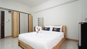 A hotel room with a bed, a wardrobe, a desk, and a refrigerator.