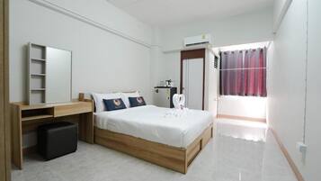 A bedroom with a bed, a desk, a wardrobe, and a window with curtains.