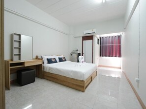 Relax in a serene bedroom with a neatly made bed, wooden desk, and comfortable seating area.