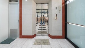En moderne elevatordøråbning med en glasdør, en væg med røde og hvide fliser og en metalventil.