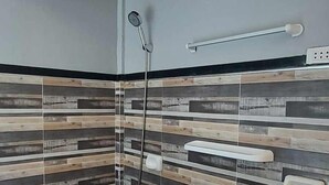 A bathroom with a shower, toilet, and hand dryer. - B&F Travellers Inn (Daanbantayan)