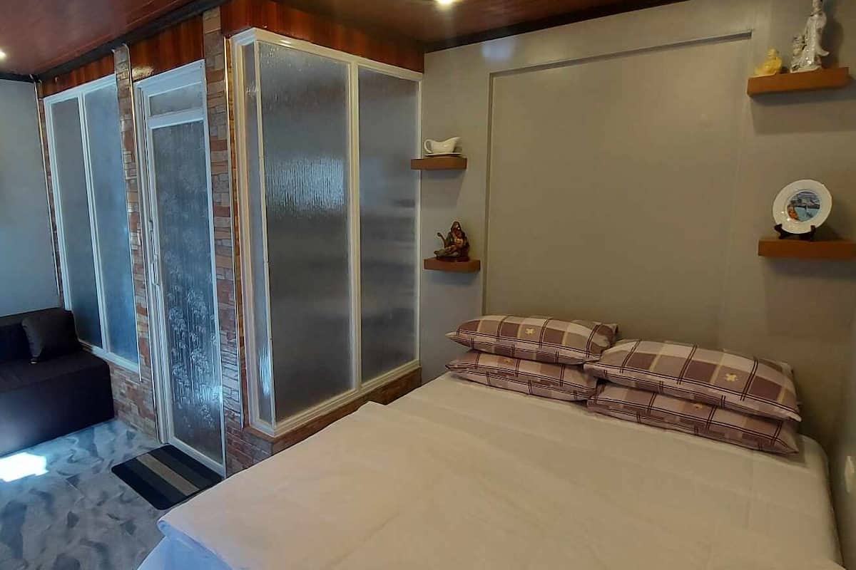 A bedroom with a bed, a wardrobe, and a small shelf with decorative items.