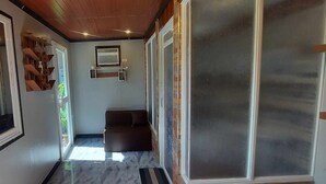 A hallway with a brown sofa, a wall-mounted air conditioning unit, and a glass door. - B&F Travellers Inn (Daanbantayan)