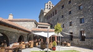 A courtyard with outdoor seating, stone buildings, and a bell tower.