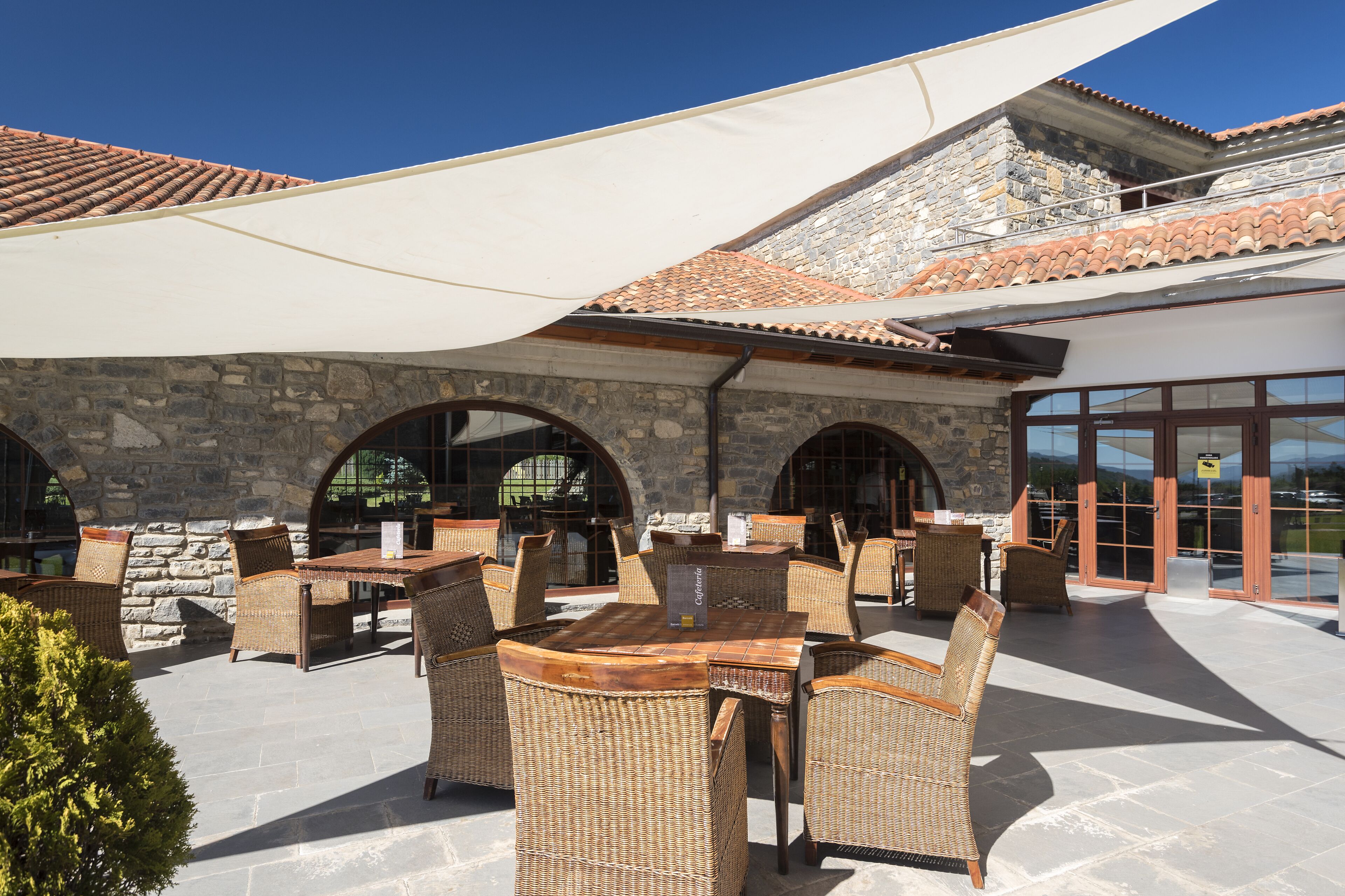 Un patio al aire libre con mobiliario de mimbre y paredes de piedra.