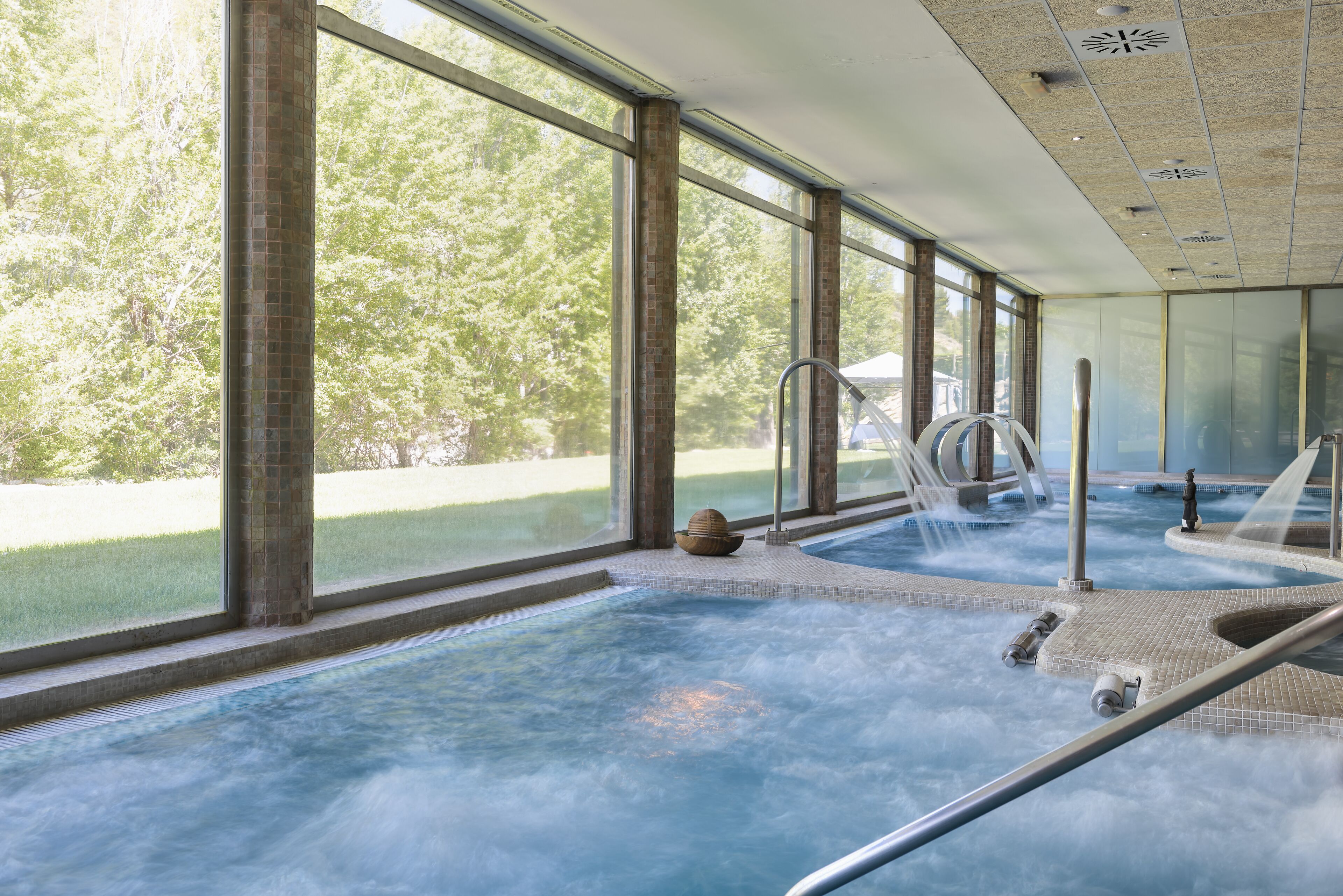 Un área de spa con hidromasaje, ventanas amplias y vistas a árboles.