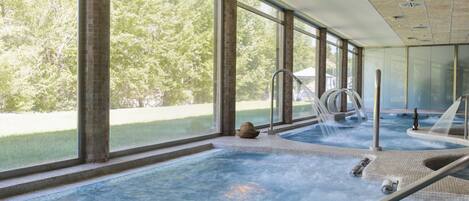 Un área de spa con hidromasaje, ventanas amplias y vistas a árboles.