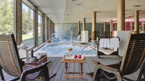 A spa area with a hot tub, wooden chairs, and a table with towels and a pitcher.