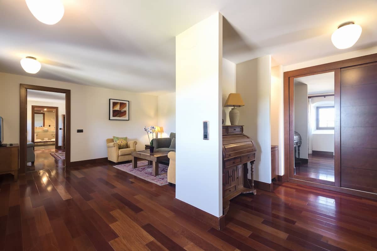 Uma sala de estar espaçosa com piso de madeira, um sofá, uma mesa de centro e um piano.