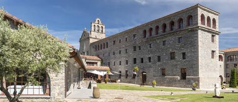 A historic stone building with a courtyard, a bell tower, and a covered outdoor seating area.