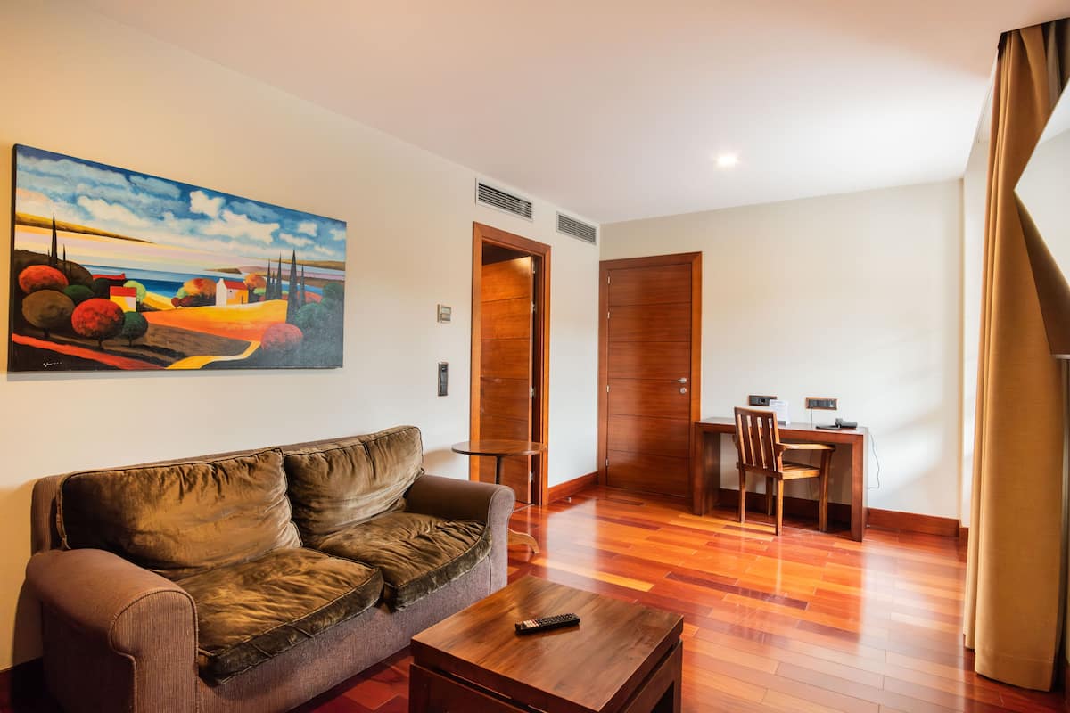 Uma sala de estar com um sofá de couro marrom, uma mesa de centro de madeira e um quadro na parede.