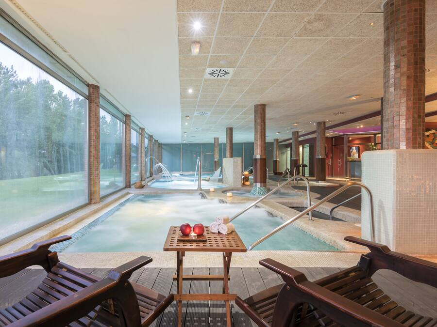 A spa area with a hot tub, wooden chairs, and a table with apples and a candle.