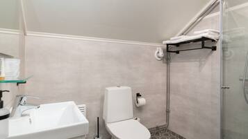 Un baño con lavamanos, inodoro y ducha blancos.