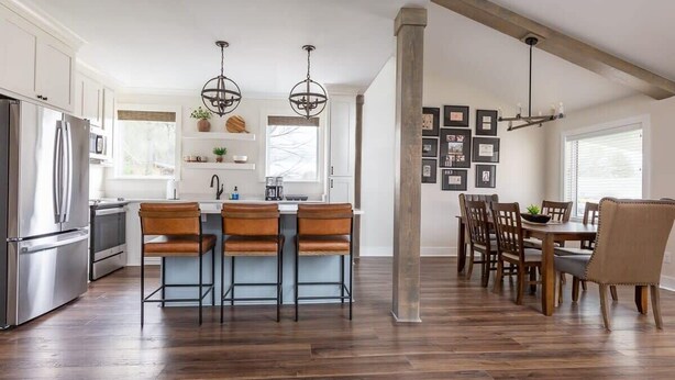 A modern kitchen with a central island, bar stools, and a dining area with wooden chairs. - Luxury Cottage,  Sleeps 12 , Great Location: minutes to sports complex (Ruston)
