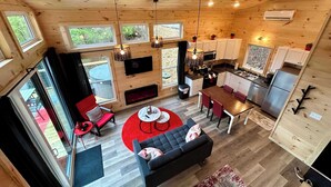 A spacious cabin with a kitchen, dining area, and living room, featuring large windows and wooden walls.