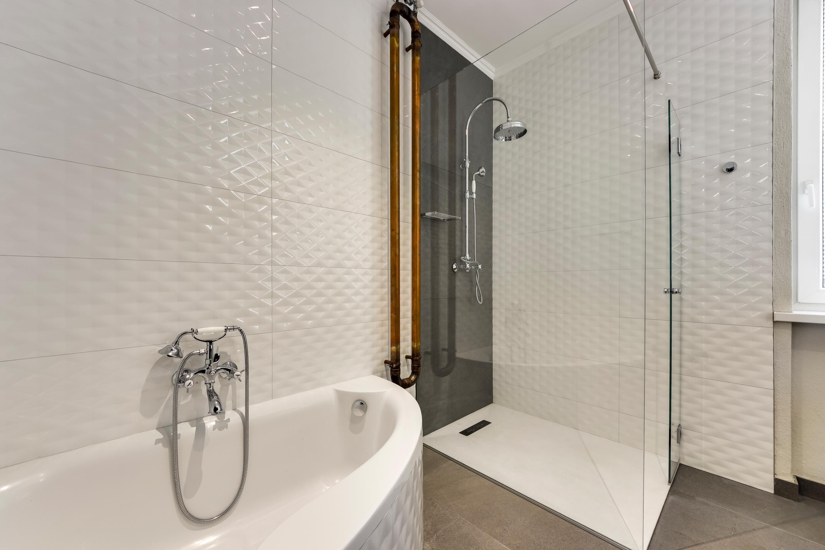 Un baño moderno con una bañera independiente, ducha con mampara de vidrio y puerta de madera.