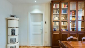 Une pièce avec une porte blanche, un meuble en bois rempli de livres et une table à manger avec des chaises.