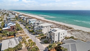 Zona residencial costeira com casas modernas, uma praia e céu claro.