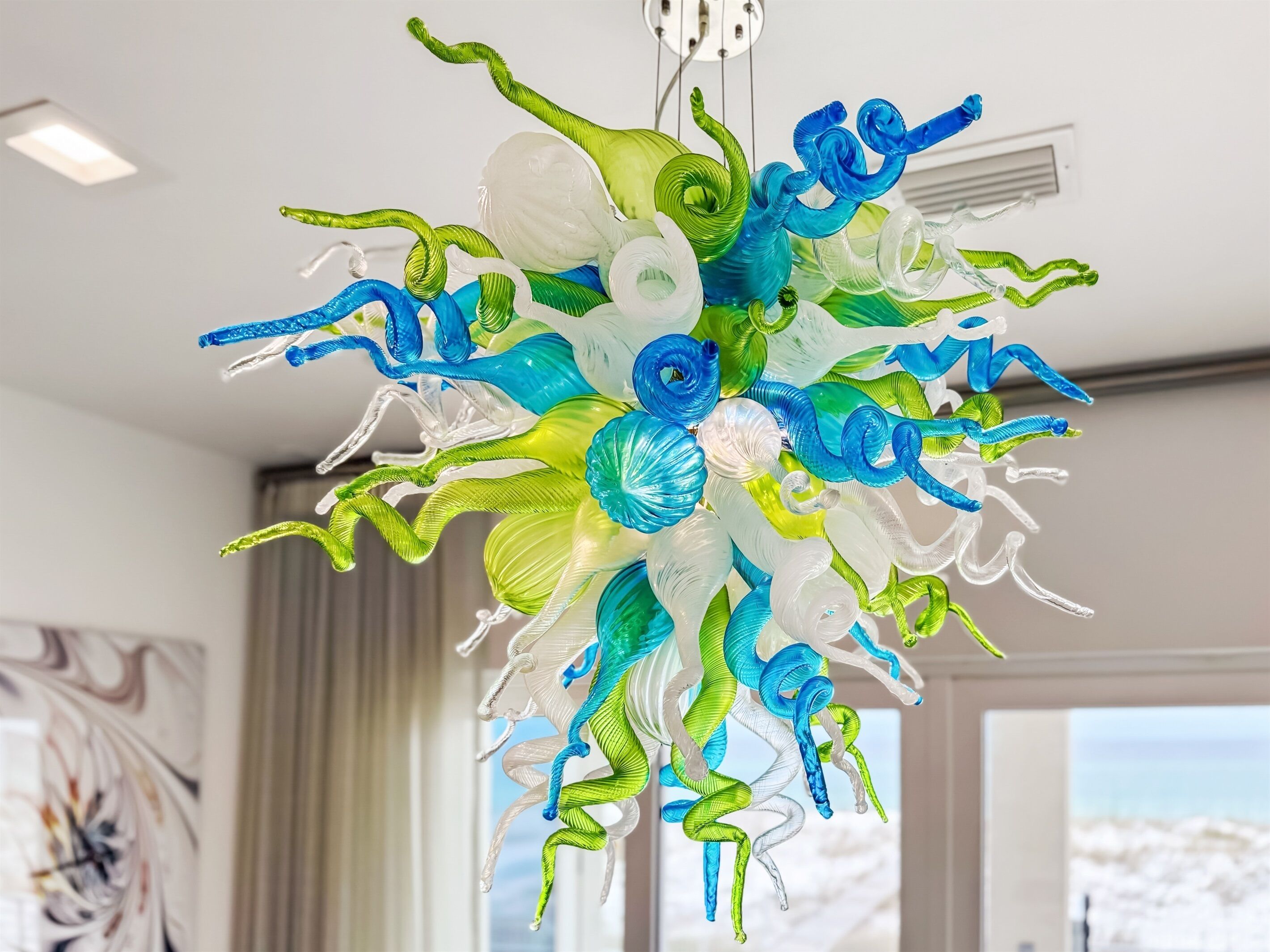 Un lustre composé de plusieurs éléments en verre, déclinés dans les couleurs bleu, vert et blanc.
