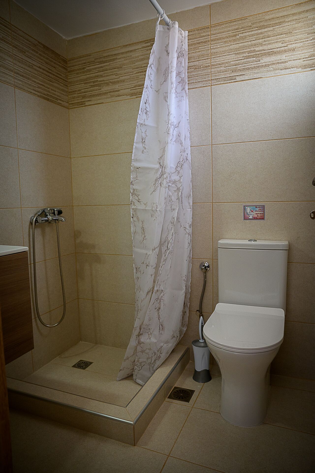 Un baño pequeño con ducha, inodoro y secamanos.