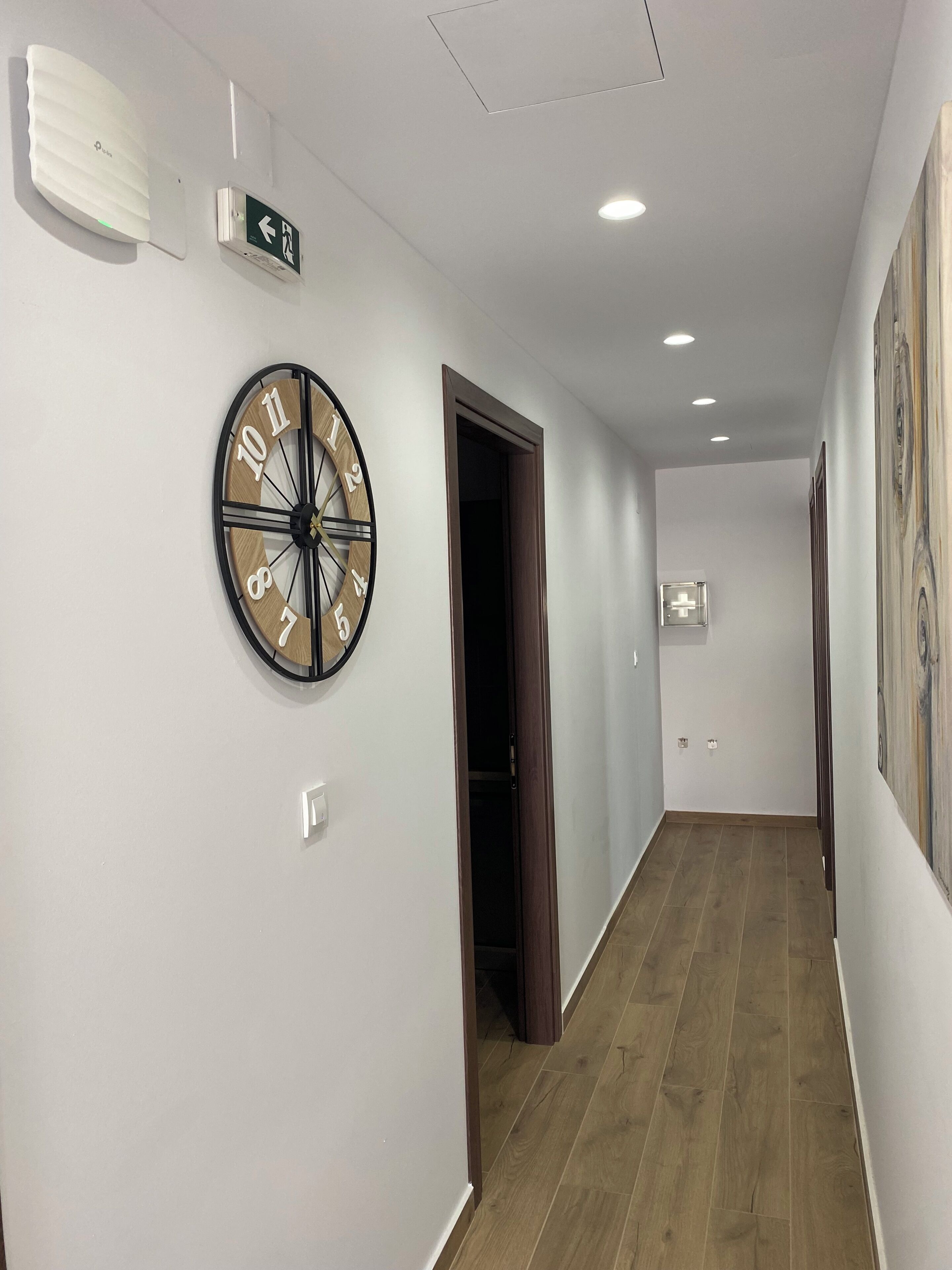 A hallway with a wall clock, a door, and a light switch.