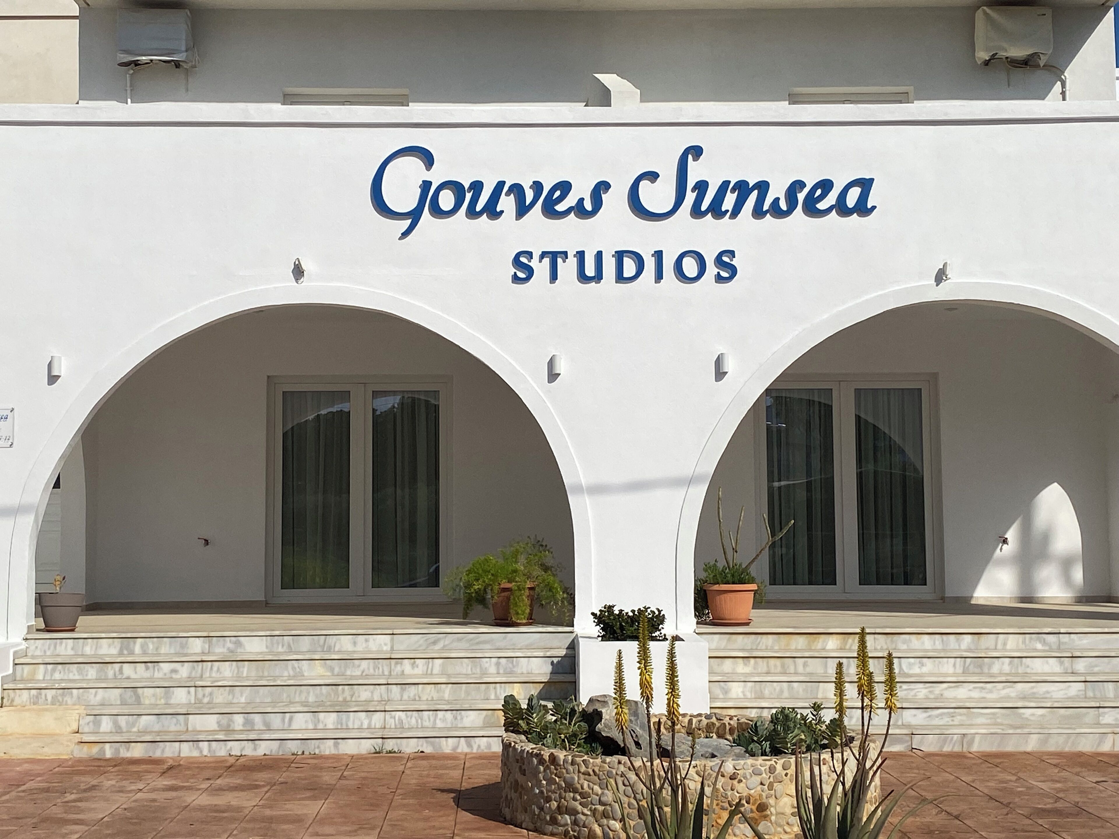 A building with the sign 'Gouves Simsea Studios' and two arched windows.