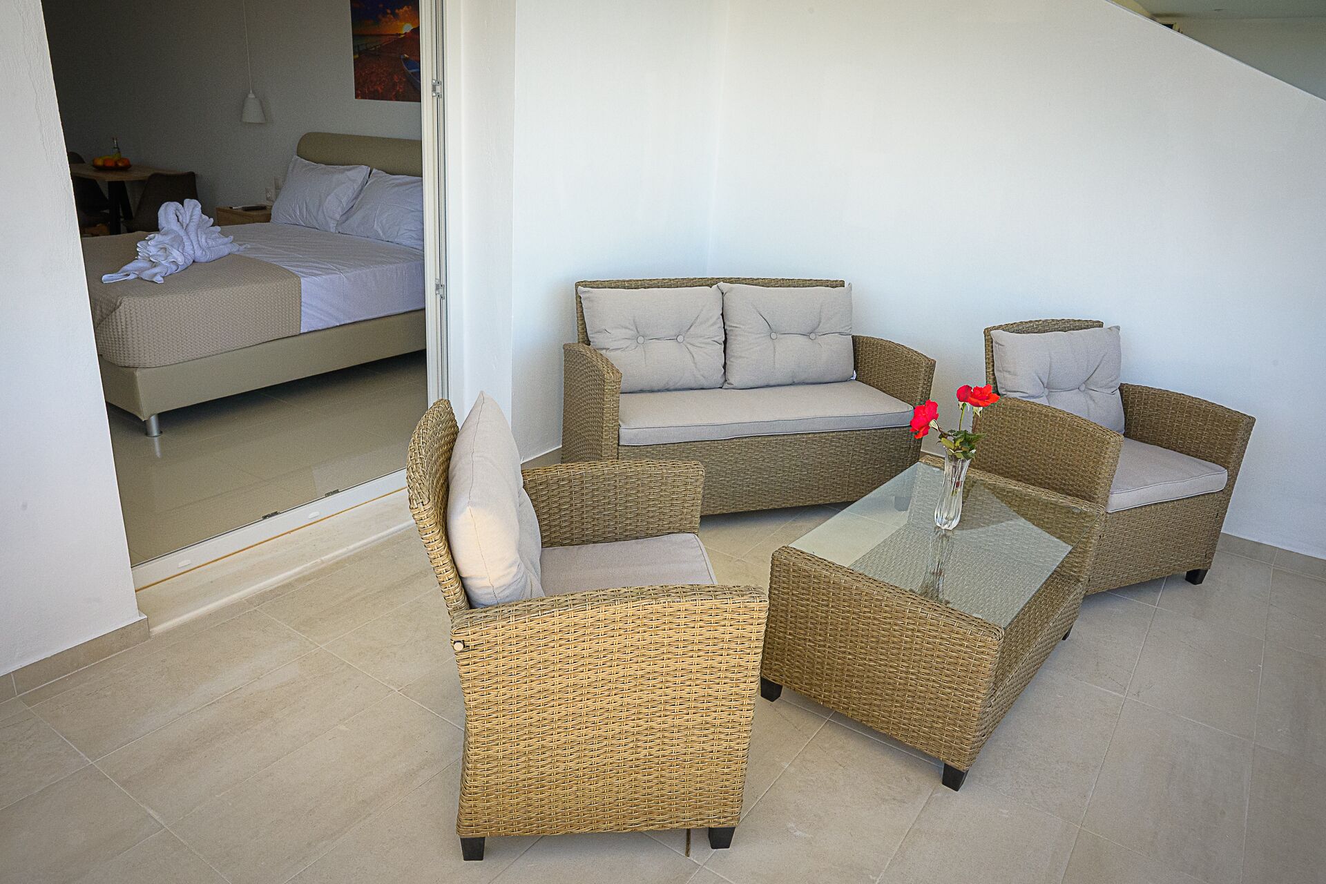 Une pièce comprenant un lit, un canapé, deux fauteuils et une petite table sur laquelle est posé un vase de fleurs.