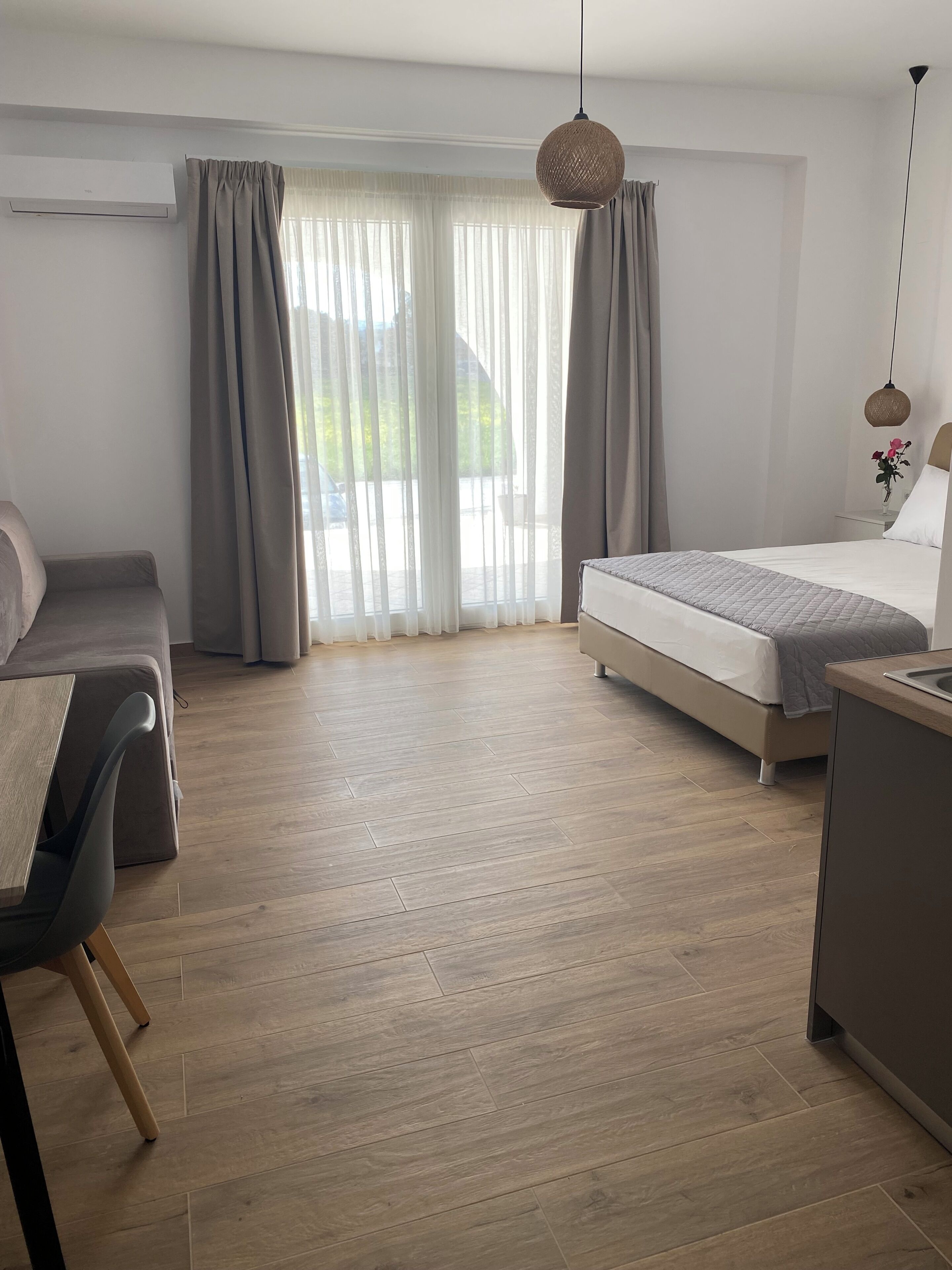 Una habitación de hotel moderna con cama, escritorio, silla y un ventanal con cortinas.