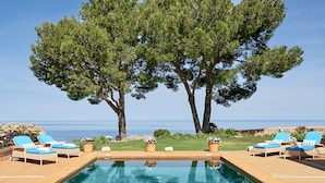 Zona de piscina con sillas de descanso y vista al mar.