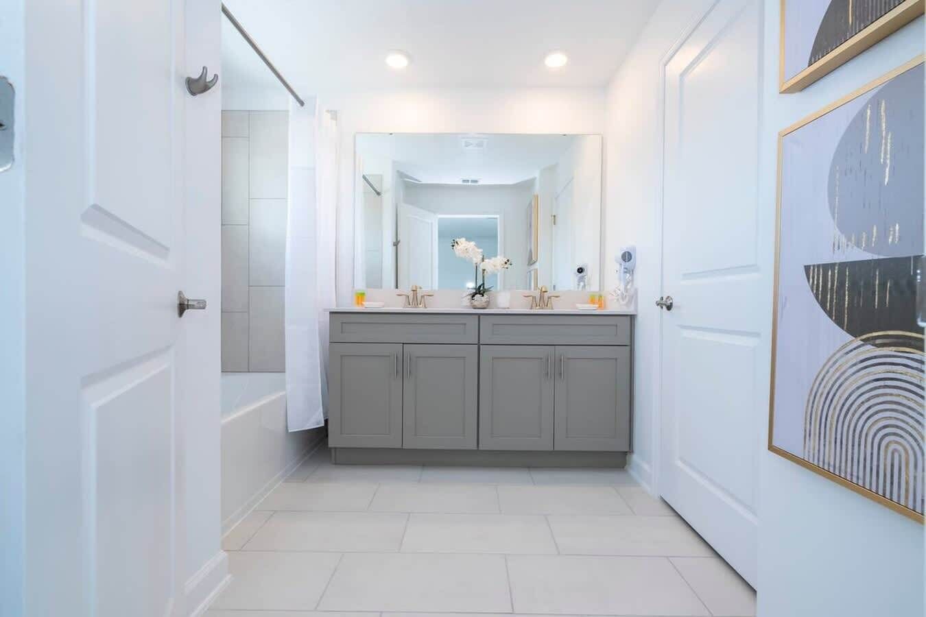 Un baño moderno con tocador doble, un espejo grande y una zona de ducha.