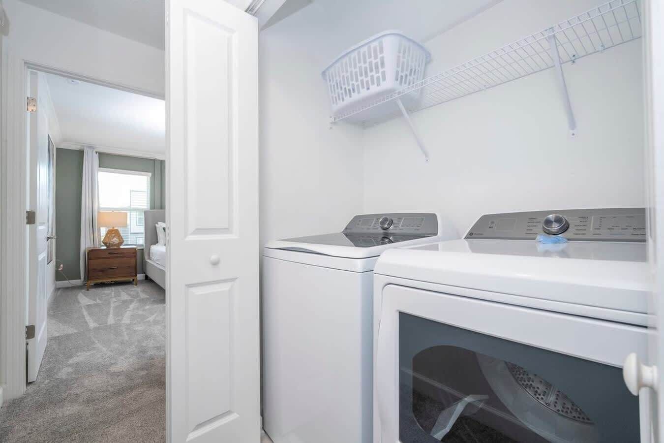 A laundry room with two washing machines and a drying rack.