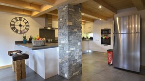 A modern kitchen with a stone pillar, a large clock, and a stainless steel refrigerator. - Apartment for 8 people in the center of Châtel - Chatel Reservation (Châtel)
