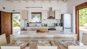 A modern kitchen with a central island, wooden cabinets, and a view of the outdoors.