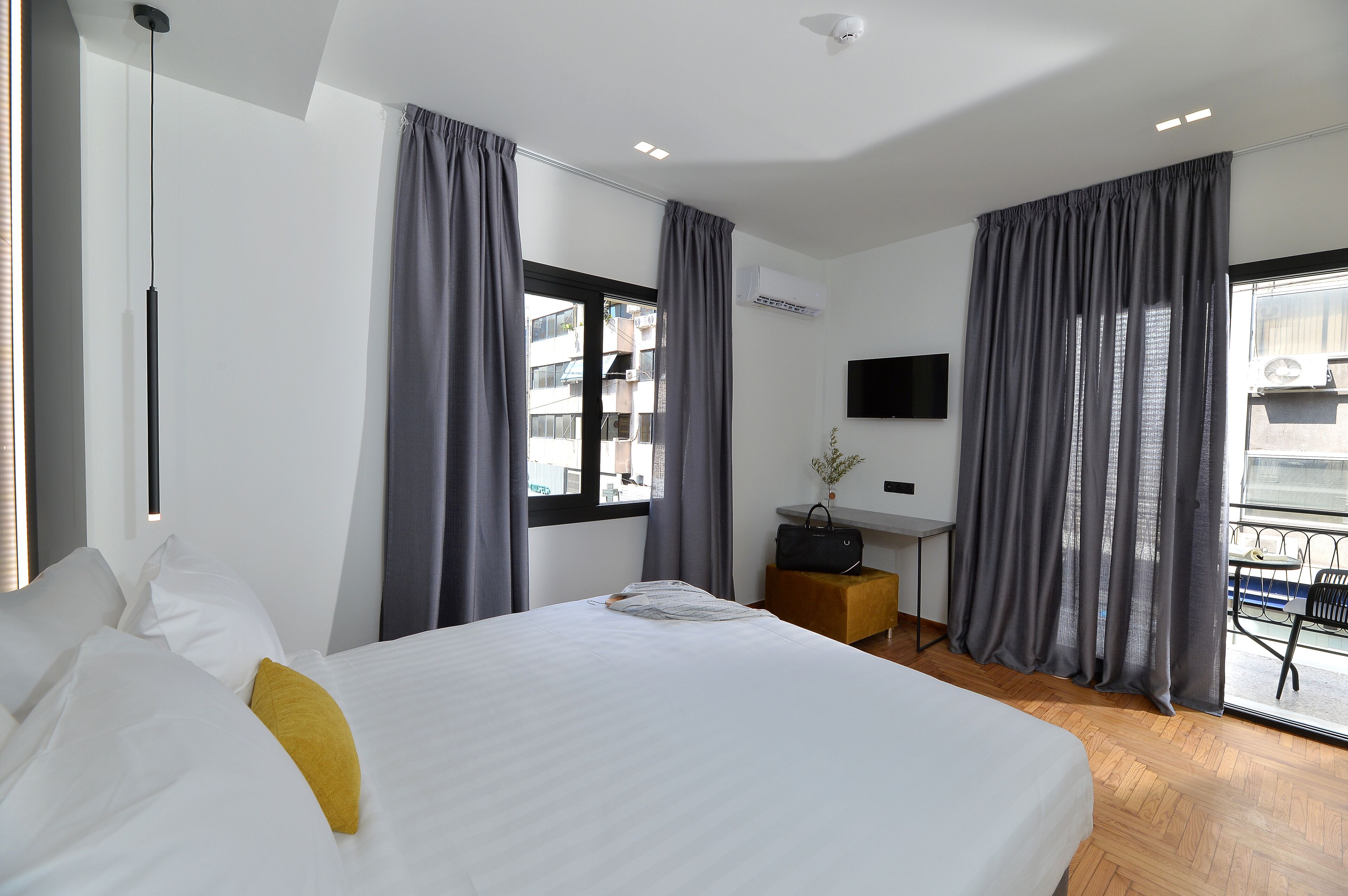 Una habitación de hotel moderna con una cama grande, un escritorio y un balcón con mesa y sillas.