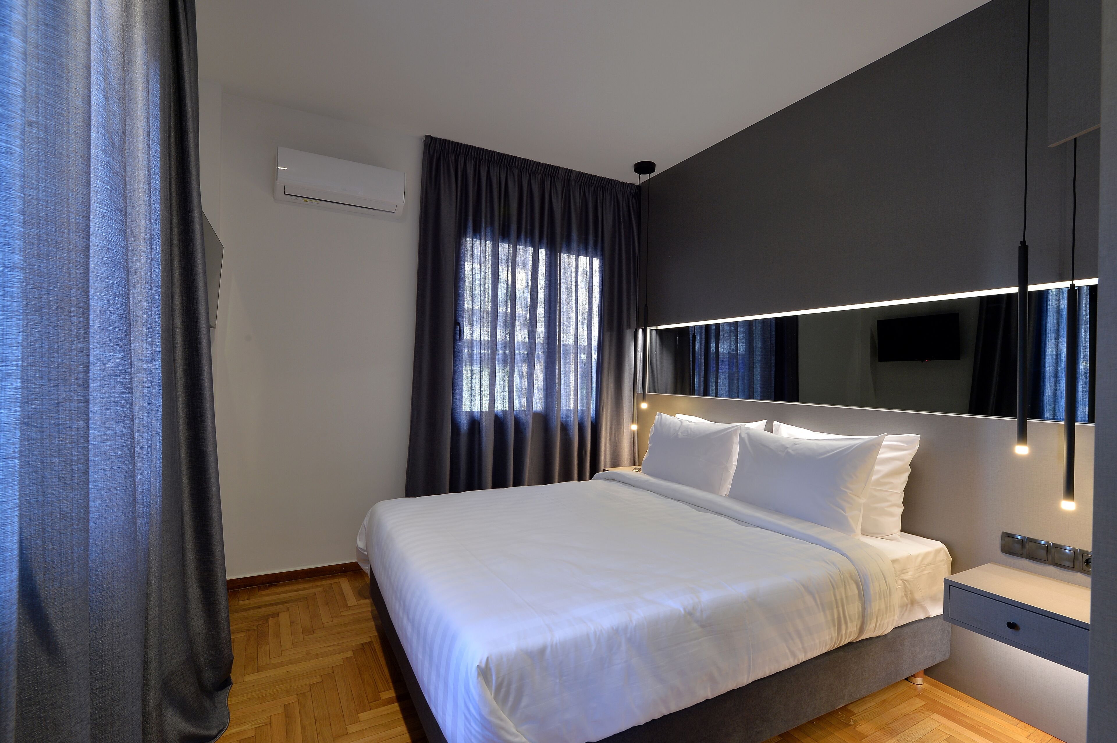 A modern hotel room with a large bed, a bedside table, and a wall-mounted TV.