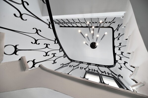Una escalera moderna con un diseño original de barandilla metálica y un aplique central.