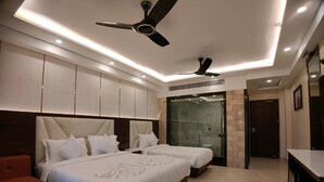 A hotel room with two beds, a desk, a sofa, and a shower area. - AGM GRAND HOTEL & SPA (Kanthi)