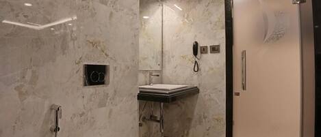 Un baño moderno con pared de mármol, inodoro, lavamanos y ducha.