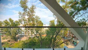 A balcony with two wicker chairs, overlooking a residential area with trees and buildings. - AGM GRAND HOTEL & SPA (Kanthi)