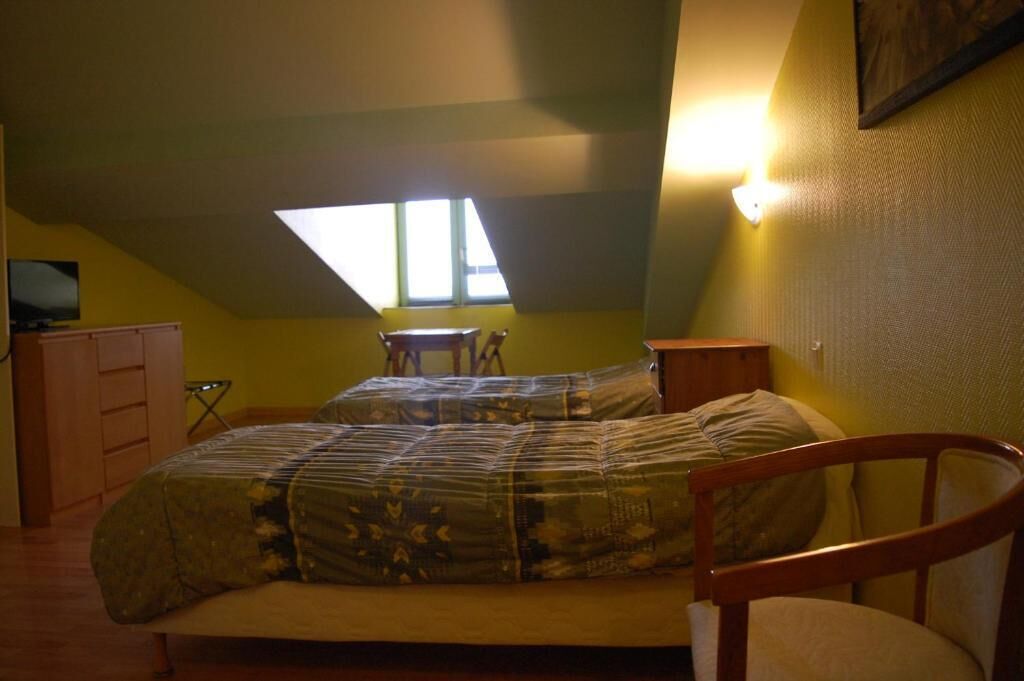 Une chambre à coucher avec un lit, une chaise, un bureau, une télévision et une fenêtre.
