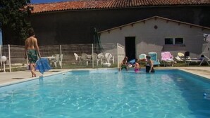 A swimming pool with clear blue water, surrounded by a white fence and several lounge chairs. - Chateâu de Faudade (Levignac)