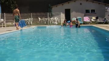 Una piscina al aire libre de temporada, sillones reclinables de piscina