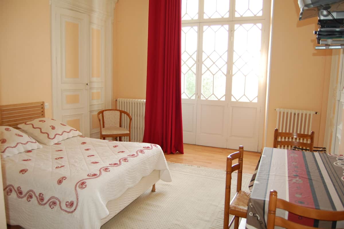 A bedroom with a bed, a table, and chairs.