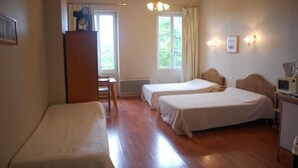A hotel room with two single beds, a wooden desk, a chair, a small kitchenette, and a window with curtains. - Chateâu de Faudade (Levignac)