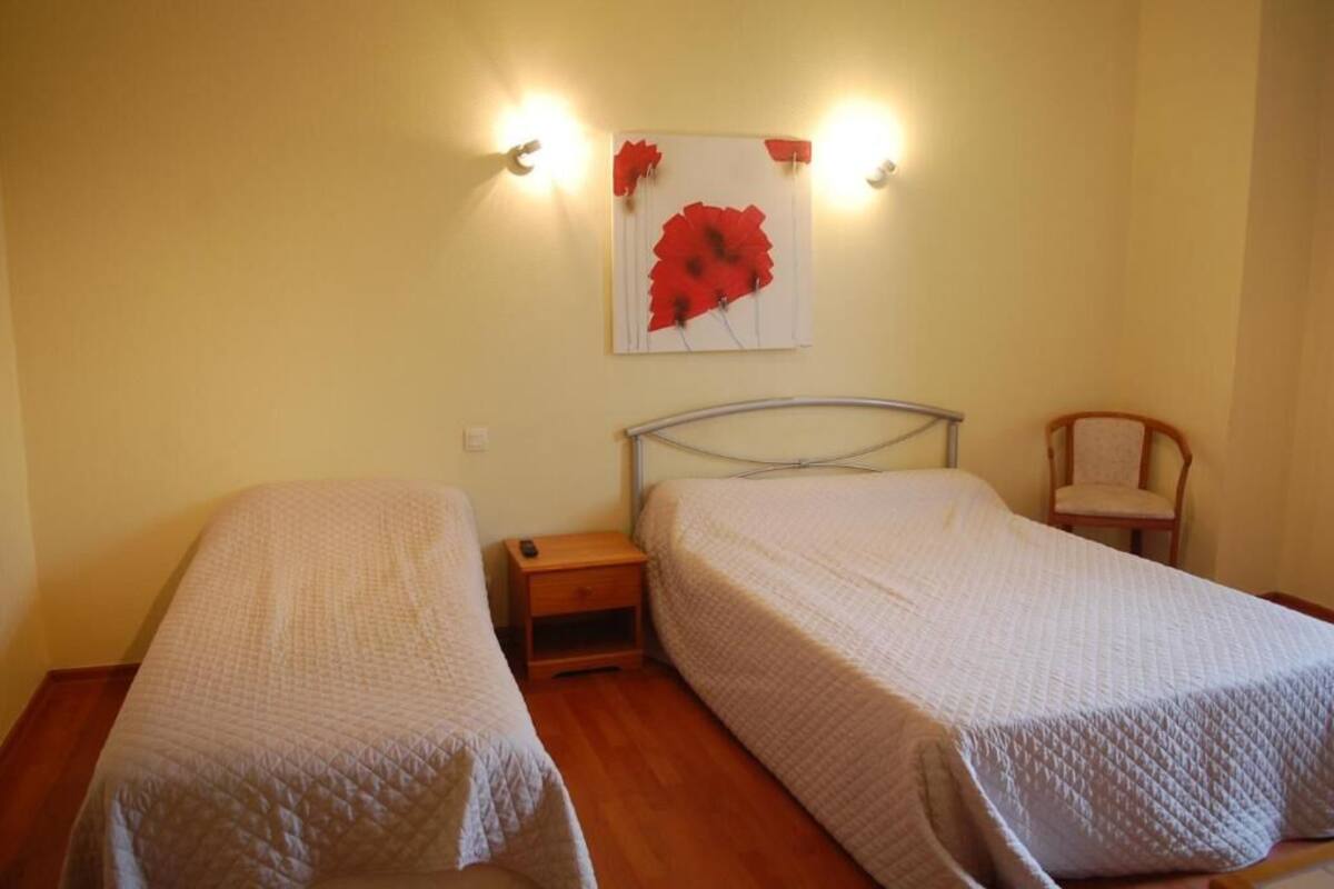 A room with two single beds, a nightstand, a chair, and a wall-mounted artwork.