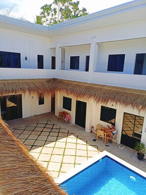 A courtyard with a swimming pool, thatched roof, and tiled flooring. - Camotes Backpackers Hostel (San Francisco)