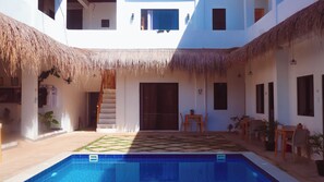 A pool area with a tiled deck, a staircase, and a door leading to an upper level. - Camotes Backpackers Hostel (San Francisco)