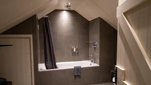 A modern bathroom with a freestanding bathtub, a towel rack, and a shower curtain.