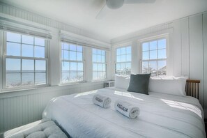 Quarto com uma cama grande, duas janelas e vista para o mar.