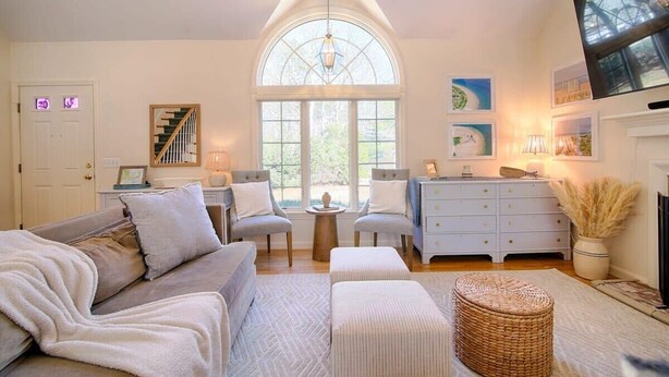 Un salon chaleureux avec une grande fenêtre, une cheminée et un escalier.